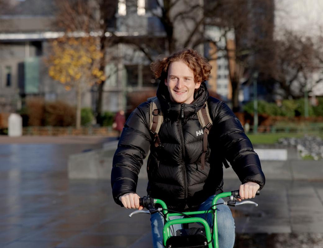 A smiling student on a bike